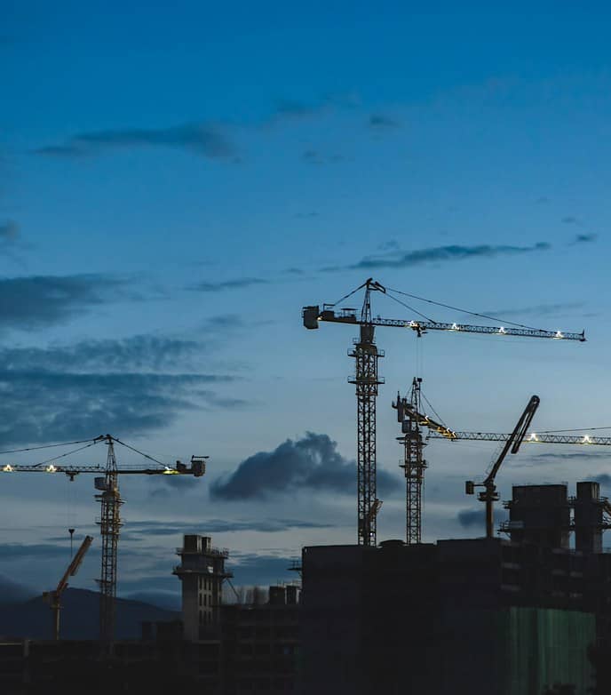 Construction cranes on a building site at dusk